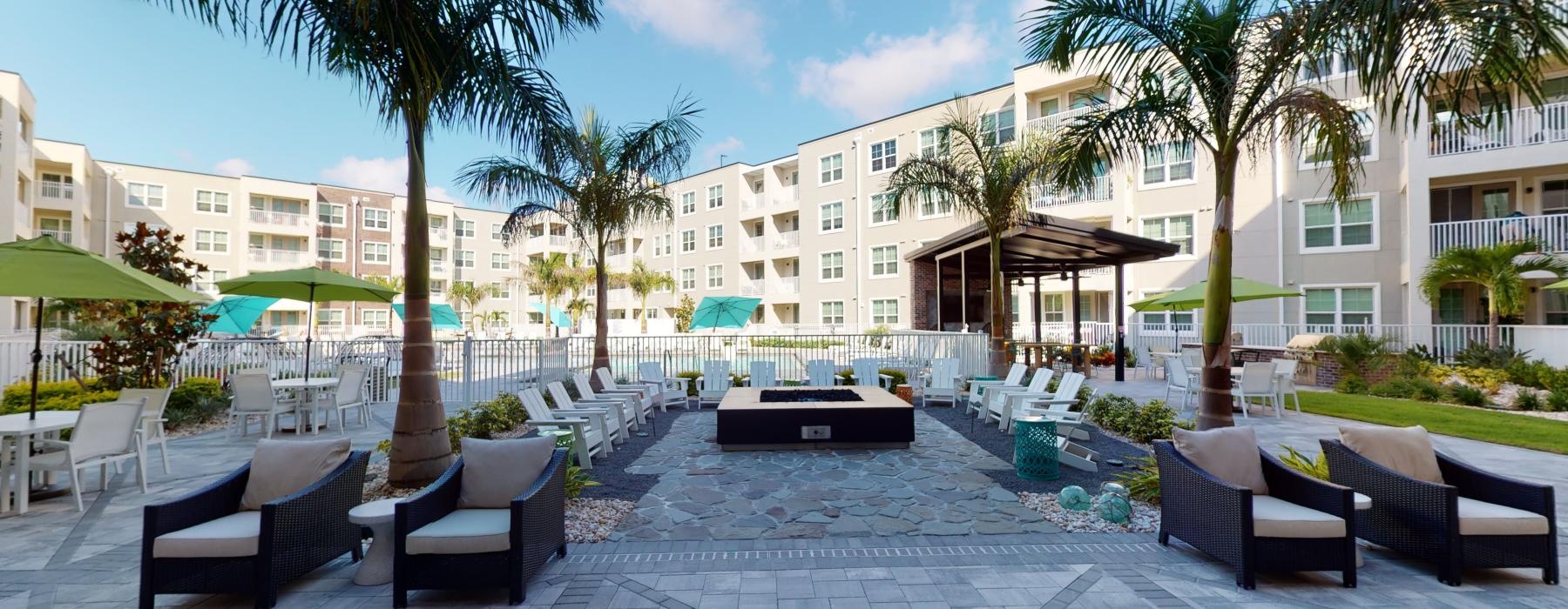 a patio with chairs and tables and umbrellas by a building